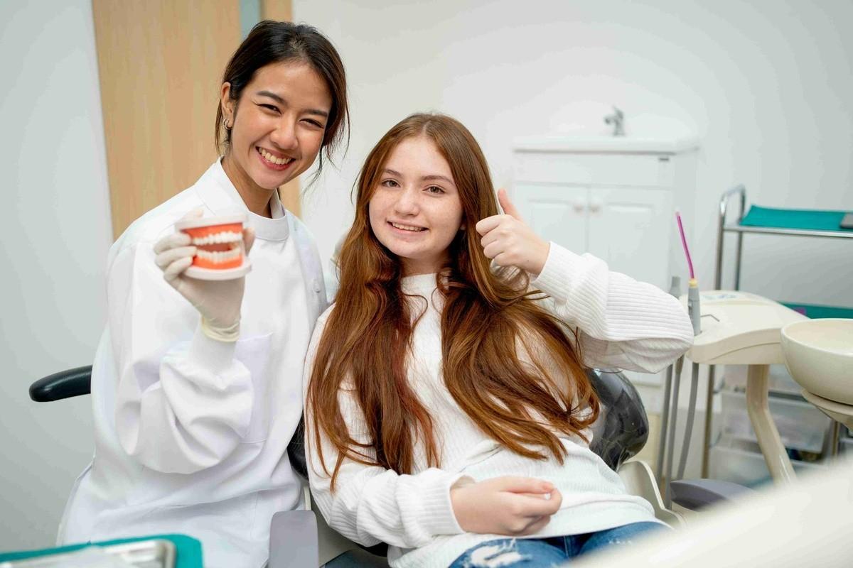 Dentist explaining dental bridge treatment to a patient using a dental model